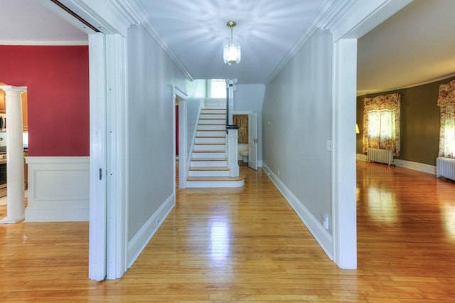hallway featuring radiator heating unit, stairway, and light wood-style floors