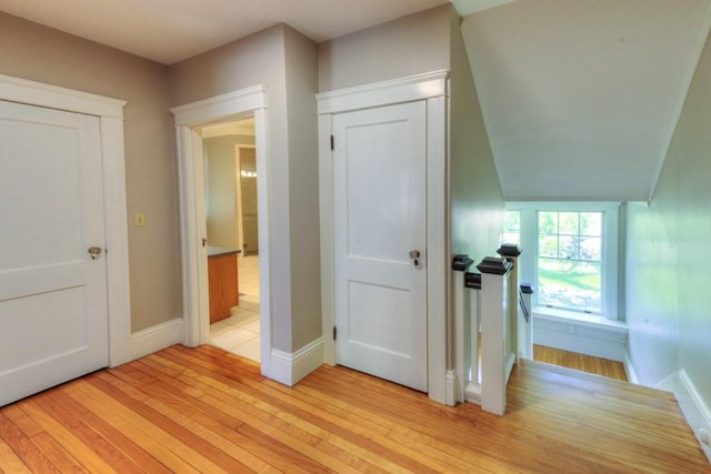 corridor with baseboards and light wood finished floors