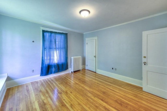 empty room with baseboards, ornamental molding, radiator heating unit, and light wood-style floors