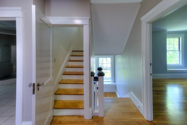 stairway with a healthy amount of sunlight, baseboards, and wood finished floors