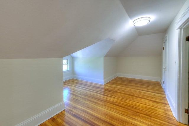 additional living space featuring light wood-type flooring, baseboards, and vaulted ceiling