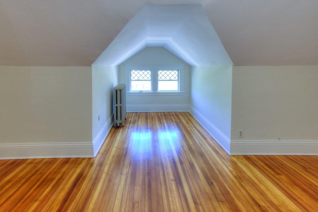 bonus room featuring baseboards, radiator, lofted ceiling, and wood finished floors