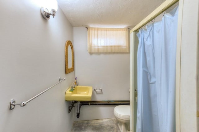 full bath with a sink, a textured ceiling, curtained shower, and toilet