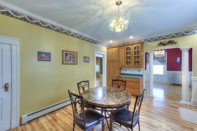 dining area with crown molding, light wood-type flooring, a baseboard heating unit, a notable chandelier, and ornate columns