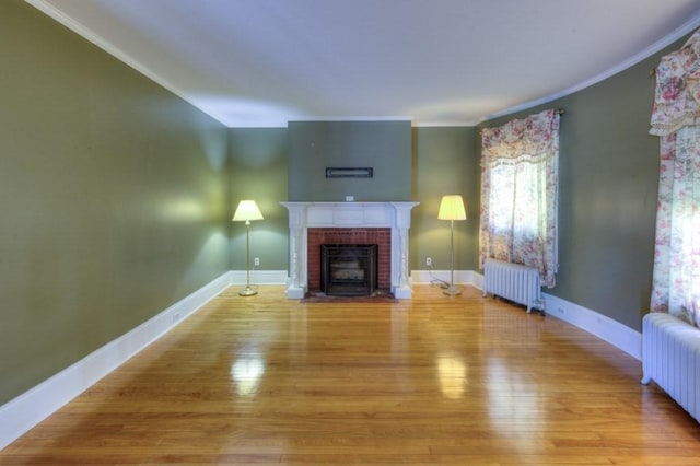 unfurnished living room with ornamental molding, light wood-type flooring, radiator heating unit, and a fireplace