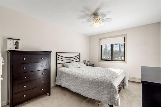 carpeted bedroom featuring a baseboard heating unit and ceiling fan