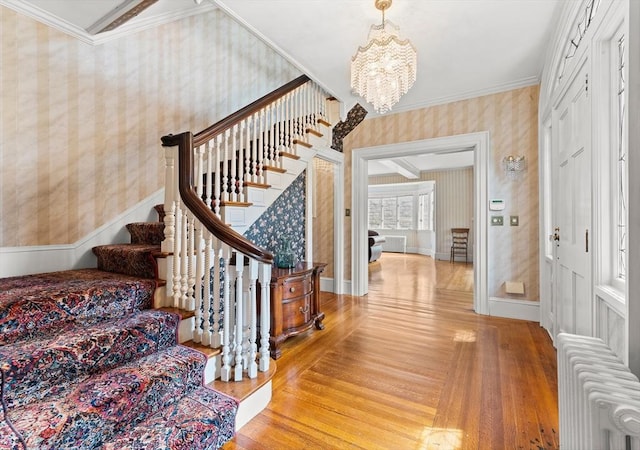 116 Adin St, Hopedale, MA 01747 - foyer entrance with wallpapered walls, wood finished floors, stairway, radiator, and a chandelier