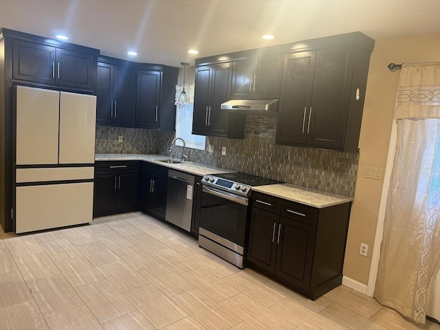 kitchen with appliances with stainless steel finishes, backsplash, a sink, and under cabinet range hood