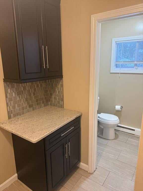 bathroom with a baseboard heating unit, baseboards, toilet, and decorative backsplash