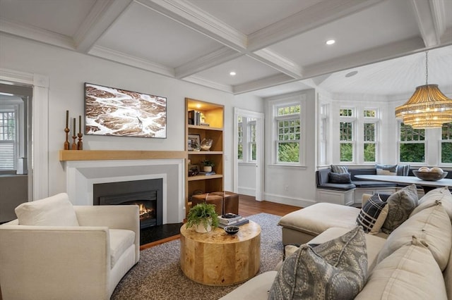 living area with coffered ceiling, baseboards, a healthy amount of sunlight, a lit fireplace, and wood finished floors