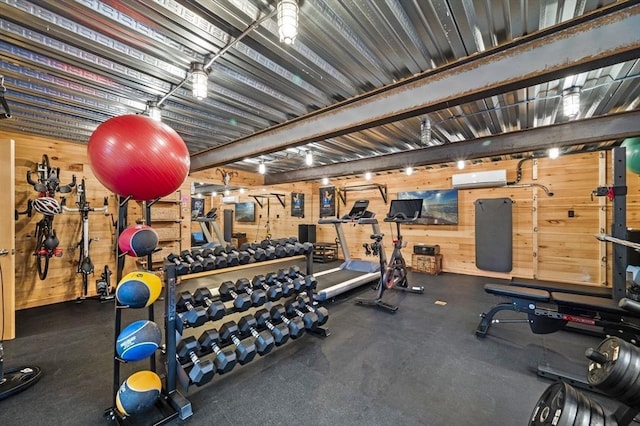 workout room featuring wood walls and a wall unit AC