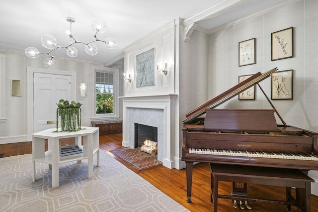 sitting room with baseboards, an inviting chandelier, crown molding, wood finished floors, and a fireplace
