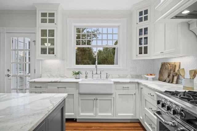 kitchen featuring backsplash, white cabinetry, range with two ovens, and a sink