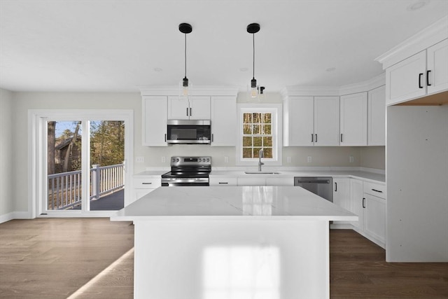 kitchen with appliances with stainless steel finishes, a center island, pendant lighting, and sink