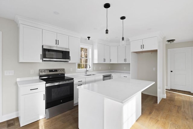 kitchen featuring white cabinetry, sink, pendant lighting, a kitchen island, and appliances with stainless steel finishes