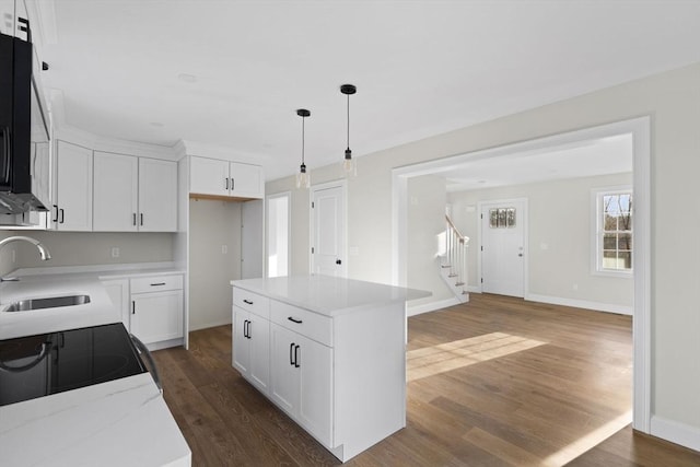 kitchen with pendant lighting, a center island, dark wood-type flooring, white cabinets, and sink