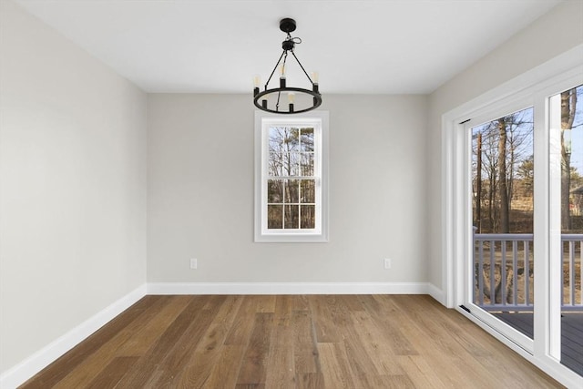 unfurnished dining area featuring plenty of natural light, light hardwood / wood-style flooring, and an inviting chandelier