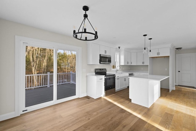 kitchen with appliances with stainless steel finishes, decorative light fixtures, light hardwood / wood-style flooring, a center island, and white cabinetry