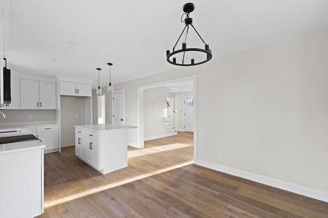 kitchen with an inviting chandelier, white cabinets, hardwood / wood-style floors, a center island, and hanging light fixtures