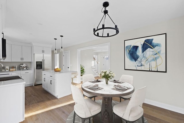 dining room featuring sink, wood-type flooring, and a notable chandelier