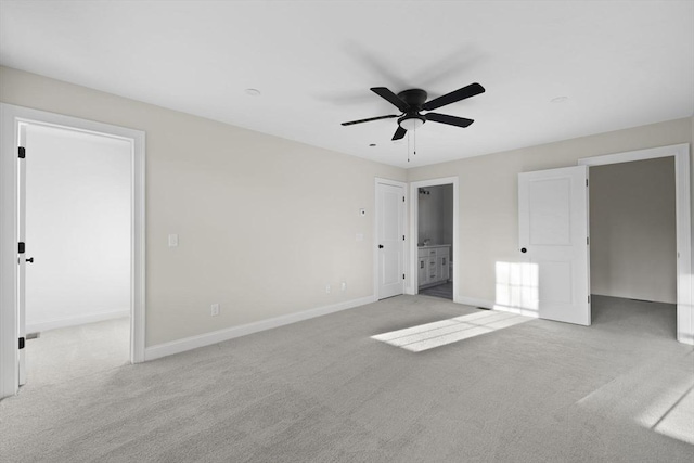 unfurnished bedroom featuring light carpet, connected bathroom, ceiling fan, and a walk in closet