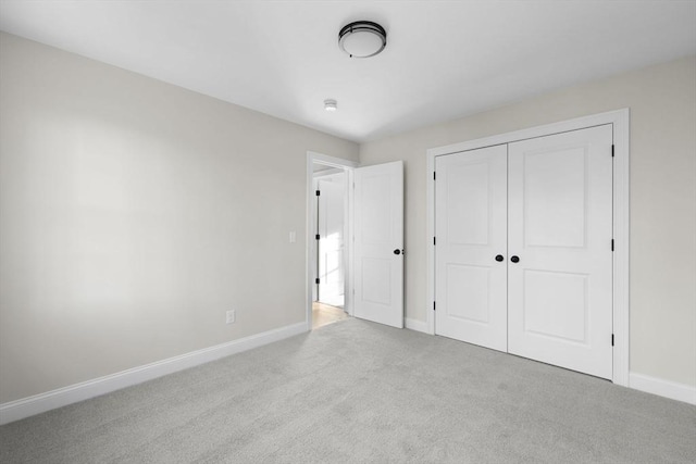 unfurnished bedroom featuring light carpet and a closet