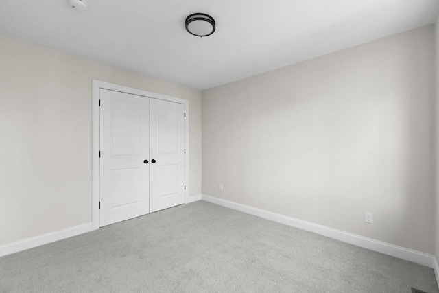 unfurnished bedroom with light carpet and a closet