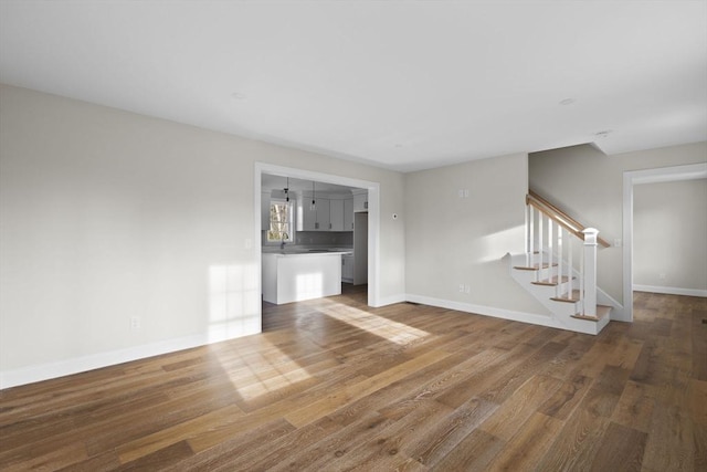 unfurnished living room with hardwood / wood-style floors and sink