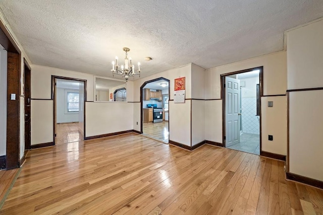 2 Hammond Ct, Quincy, MA 02169 - unfurnished dining area featuring light wood-style flooring, a textured ceiling, arched walkways, a chandelier, and baseboards