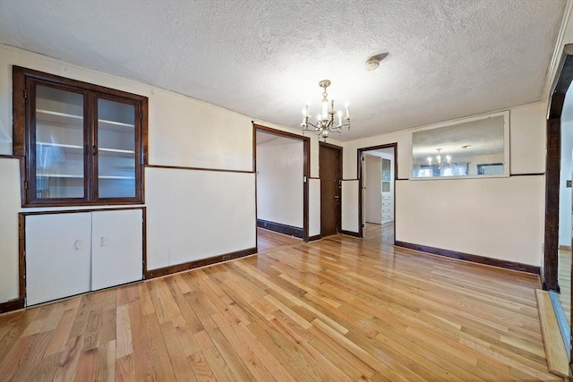 2 Hammond Ct, Quincy, MA 02169 - unfurnished dining area with a chandelier, light wood-style flooring, baseboards, and a textured ceiling