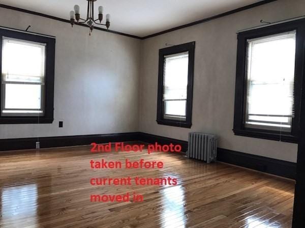 2 Hammond Ct, Quincy, MA 02169 - spare room featuring radiator, a chandelier, ornamental molding, wood finished floors, and baseboards