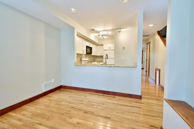 39 Bellis Cir Unit E, Cambridge, MA 02140 - unfurnished living room featuring baseboards, visible vents, a sink, and light wood-type flooring