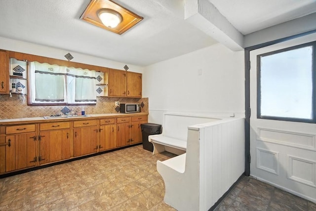 16 Laurel St, Springfield, MA 01107 - kitchen featuring stainless steel microwave, plenty of natural light, brown cabinetry, and backsplash