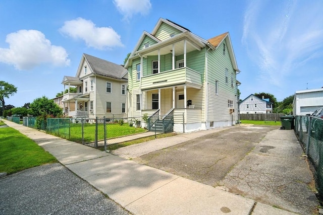 16 Laurel St, Springfield, MA 01107 - view of front facade featuring a balcony, a fenced front yard, asphalt driveway, and covered porch