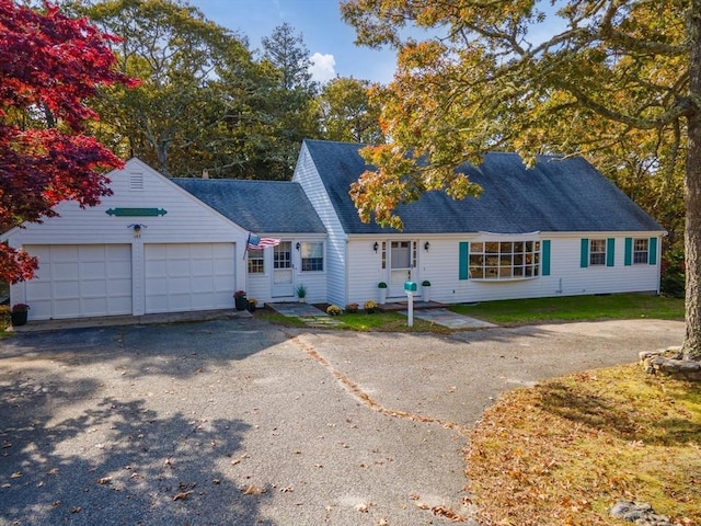 view of front of house featuring an attached garage, a shingled roof, driveway, and a front yard