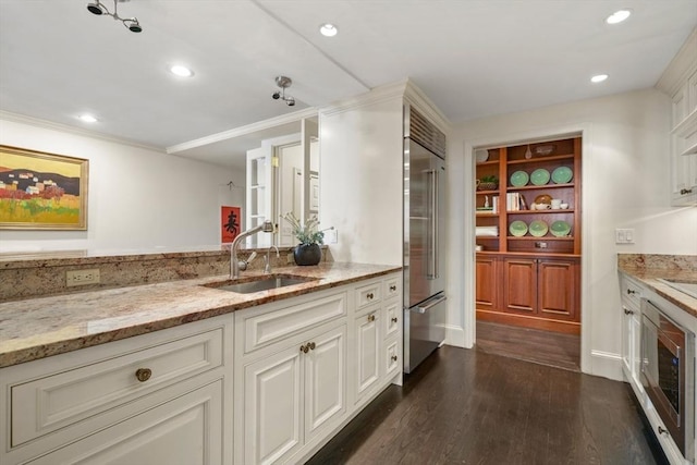 kitchen featuring stainless steel built in refrigerator, light stone counters, recessed lighting, dark wood-style floors, and a sink