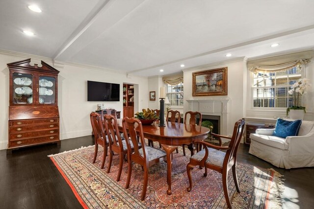 dining room with beam ceiling, dark wood-style floors, a fireplace, and crown molding