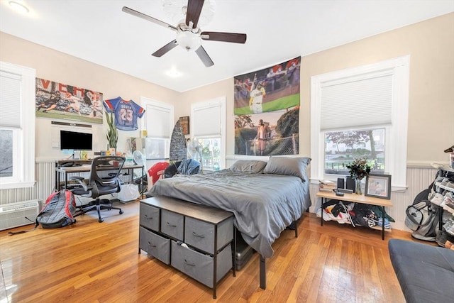 bedroom featuring ceiling fan, multiple windows, and light wood-type flooring