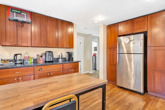 kitchen featuring dark stone countertops, stainless steel fridge, beverage cooler, and light hardwood / wood-style flooring