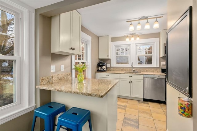 kitchen with a breakfast bar, sink, white cabinets, built in refrigerator, and stainless steel dishwasher