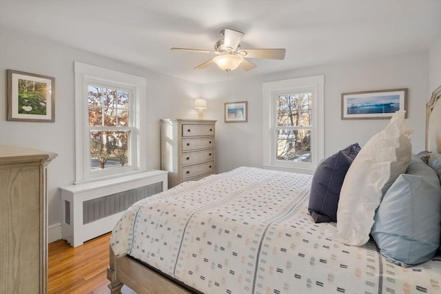 bedroom with ceiling fan, radiator, and light hardwood / wood-style floors