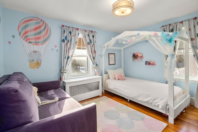 bedroom with wood-type flooring and radiator heating unit