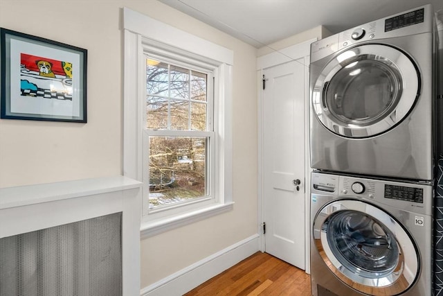 laundry area with stacked washer / dryer and light hardwood / wood-style floors