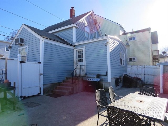 rear view of property with a wall mounted AC and a patio