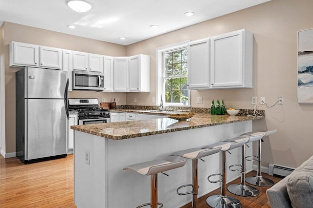26 Harvest Rd, Reading, MA 01867 - kitchen with appliances with stainless steel finishes, dark stone countertops, a peninsula, white cabinetry, and recessed lighting