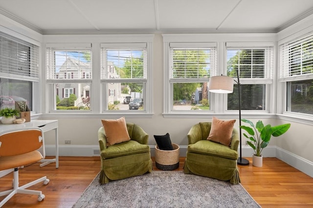 sunroom / solarium featuring healthy amount of natural light, wood finished floors, baseboards, and crown molding