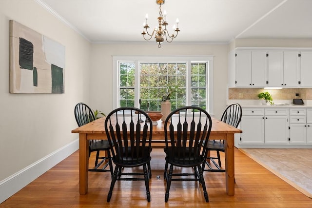 dining space featuring baseboards, a chandelier, crown molding, and light wood-style flooring
