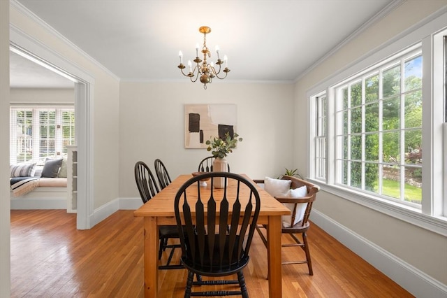 dining area featuring plenty of natural light, a chandelier, light wood-style flooring, and ornamental molding