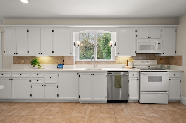 kitchen featuring white appliances, a sink, white cabinets, backsplash, and recessed lighting