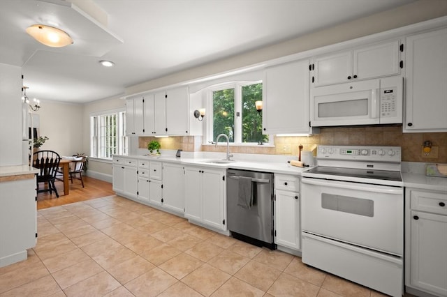kitchen featuring white appliances, a sink, light countertops, decorative backsplash, and light tile patterned flooring